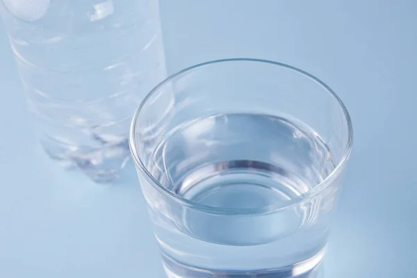 Vidrio y botella con agua sobre fondo azul — Foto de Stock