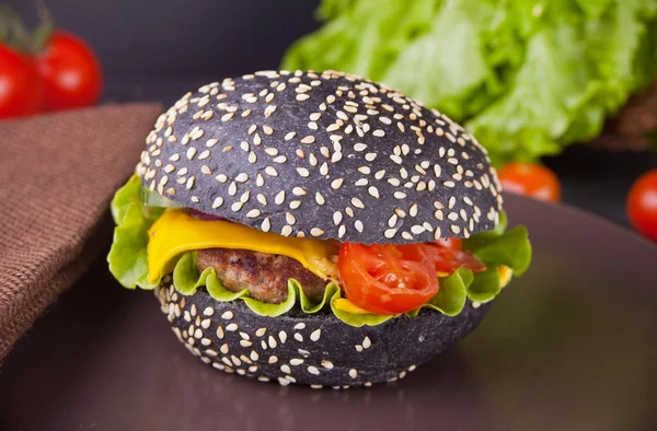 Hambúrguer preto caseiro com costeleta e legumes no prato . — Fotografia de Stock