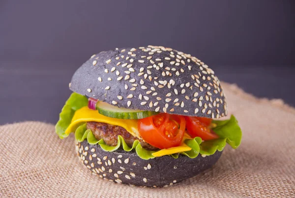 Homemade black burger with cutlet and vegetables on the napkin Royalty Free Stock Images