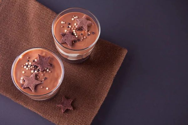 Sobremesa de chocolate em jarros de vidro em uma mesa com colher de madeira. Vista superior . — Fotografia de Stock