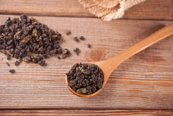 Black dry tea leaves with wooden spoon on the wooden table — Stock Photo, Image