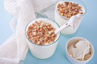 Beyaz peçete ile bir masada müsli, krem peynir ile cam yoğurt.
