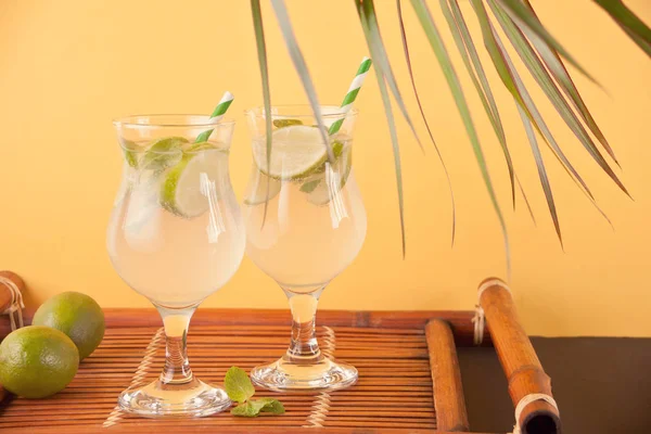 Lemonade or mojito cocktail with lemon and mint, cold refreshing drink or beverage on the yellow background. — Stock Photo, Image