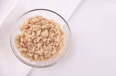 Beyaz masada beyaz peçete ile cam kase pişmiş lezzetli Quinoa. Üst görünüm.