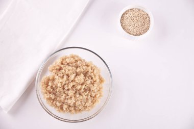 Beyaz masada beyaz peçete ile cam kase pişmiş lezzetli Quinoa. Üst görünüm.