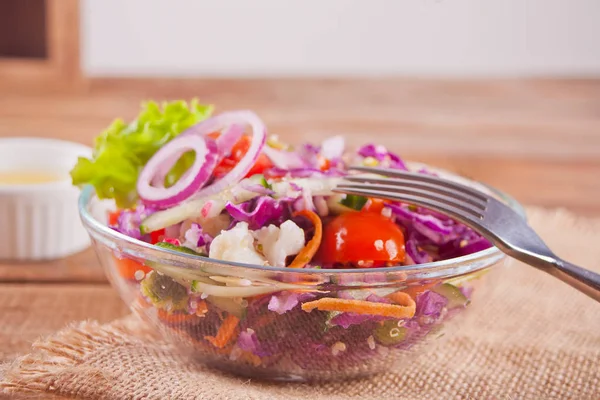 Healthy fresh salad in bowl with red cabbage, tomato, quinoa, green salad and radish on the wooden table