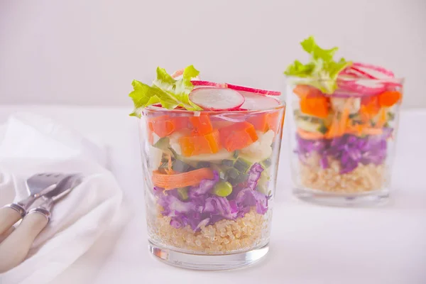 Ensalada fresca saludable en vidrio con col roja, tomate, quinua, ensalada verde y rábano en la mesa blanca —  Fotos de Stock