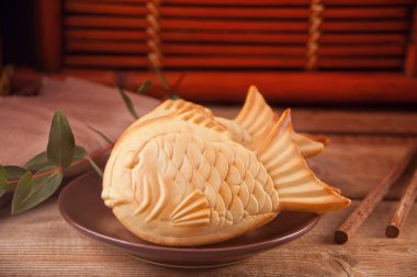 Ahşap masa üzerinde Taiyaki Japon sokak gıda balık şeklinde tatlı dolgu waffle