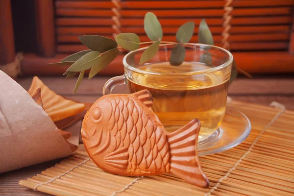 Taiyaki Japanese street food gaufre de remplissage sucrée en forme de poisson et tasse de thé vert sur table en bois — Photo