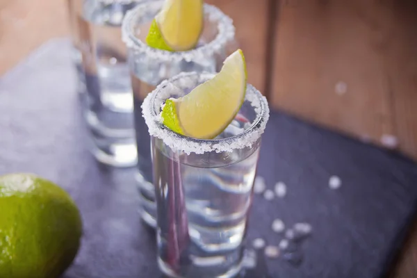 Tequila Shot mit Limette und Meersalz auf schwarzem Tablett, selektiver Fokus — Stockfoto