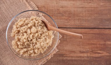 Cam kase ve ahşap arka plan üzerinde tahta kaşık pişmiş kahverengi pirinç. Kopya alanı. Üstte görüntü.