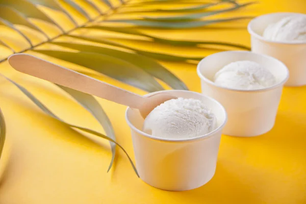Ряд ванильного мороженого и пальмовый лист на желтом фоне — стоковое фото
