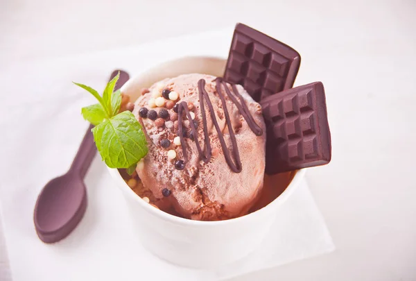 Бумажная миска шоколадного мороженого с мятным листом на белом фоне — стоковое фото