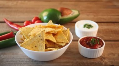 Kadın eli Meksika cipslerini alır ve sosis sosuna batırır.