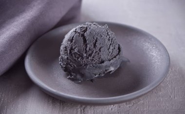 Gri bir masada gri peçete ile siyah seramik plaka üzerinde siyah dondurma