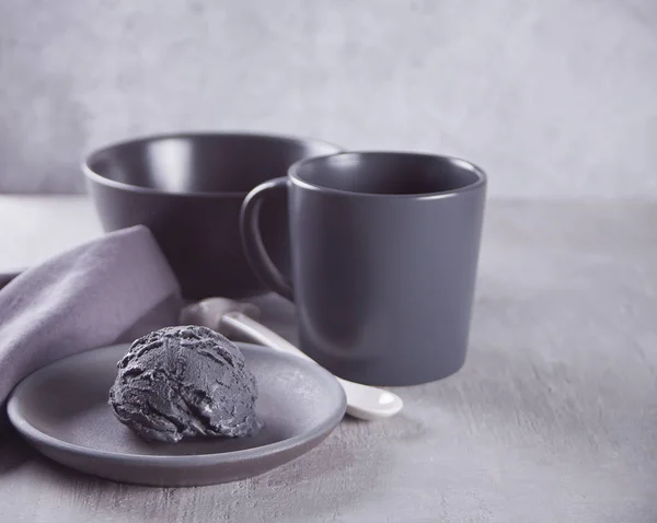Gri bir masada gri peçete ile siyah seramik plaka üzerinde siyah dondurma — Stok fotoğraf