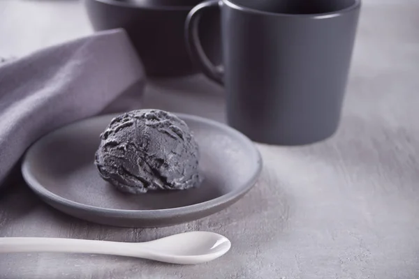 Black ice cream on a black ceramic plate with gray napkin on a gray table