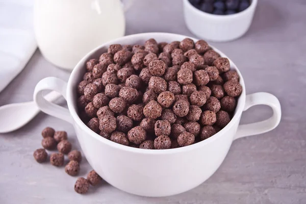 Uma tigela de bolas de chocolate seco cereal e garrafa se o leite na mesa cinza para o café da manhã saudável — Fotografia de Stock