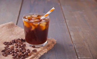 Buz küpleri ve bir masada kahve çekirdekleri ile buzlu latte kahve.