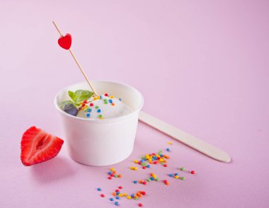 Pembe arka planda nane yaprağı, çilek ve yaban mersini ile vanilyalı dondurma