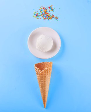 Mavi arka plan üzerinde waffle konileri ve şeker ile Vanilyalı dondurma