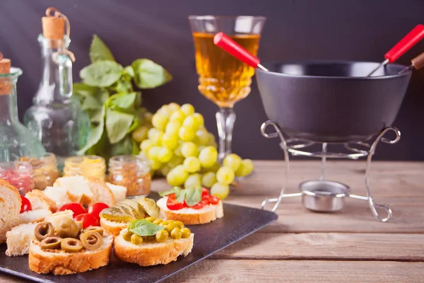Italiaanse bruschetta in assortiment op de plaat, glazen met witte wijn, druiven, Fondue. Feest of diner concept. — Stockfoto