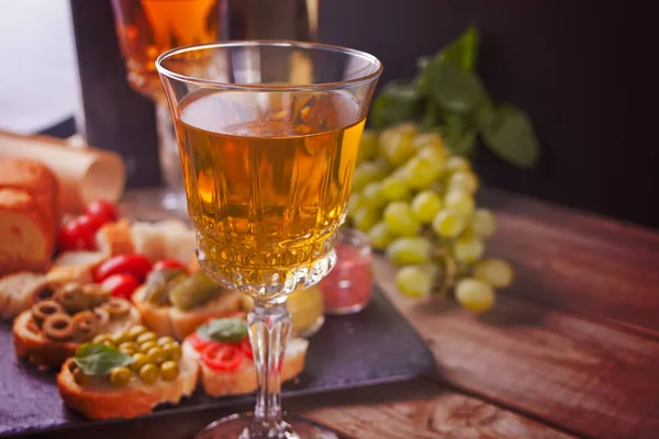 Bruschetta italiana en surtido en el plato, vasos con vino blanco, uvas. Concepto de fiesta o cena . —  Fotos de Stock