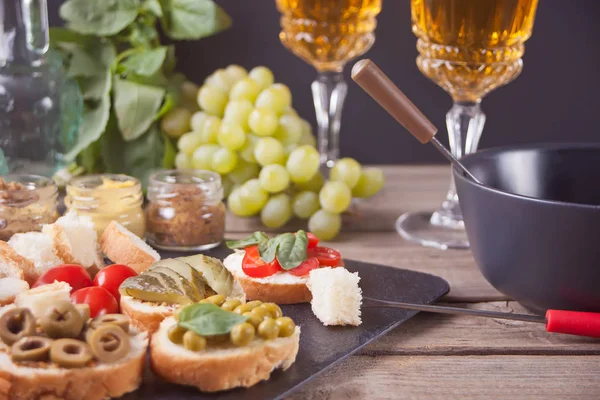 Italian bruschetta in assortment on the plate, glasses with white wine, grapes, fondue. Party or dinner concept.