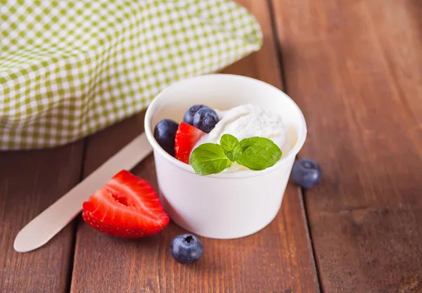 Vaniljglass med våfflor, myntblad, jordgubbar och blåbär på träbordet — Stockfoto
