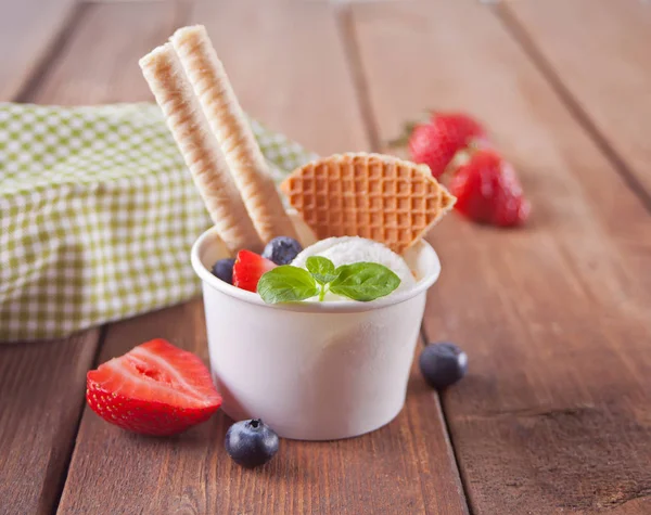 Ванільне морозиво з вафельками, листом м'яти, полуницею та чорницею на дерев'яному столі — стокове фото