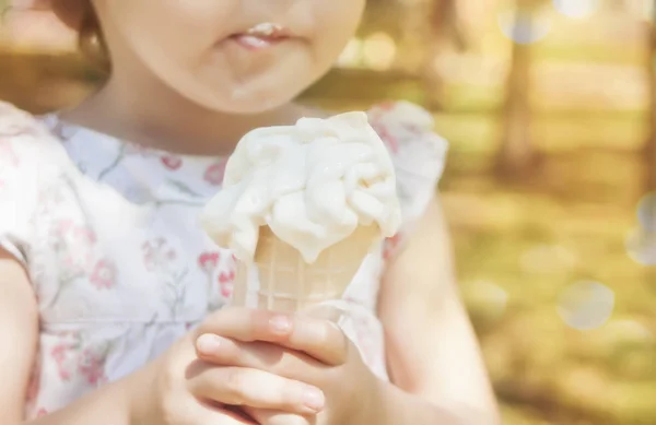 Little girl eating ice-cream. Funny child with ice-cream outdoor.