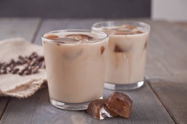 Buz küpleri ve bir masada kahve çekirdekleri ile buzlu latte kahve.