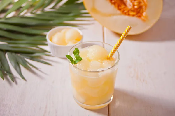 Glas mit Melonencocktail auf weißem Tisch mit Palmblatt im tropischen Thema — Stockfoto