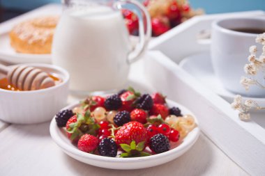 Beyaz plaka üzerinde taze tatlı meyveler, simit, kahvaltı için kahve ve bal fincan.