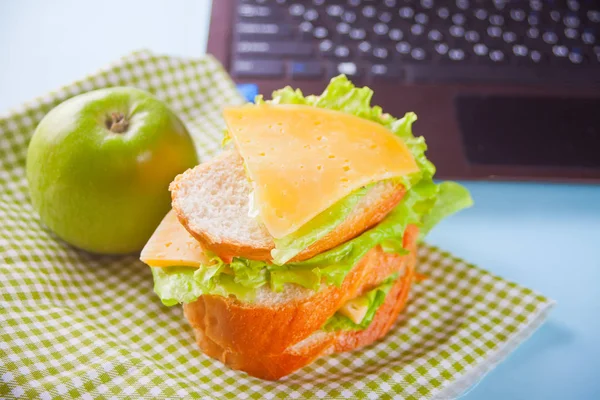 Μεσημεριανό με σάντουιτς και πράσινο μήλο και φορητό υπολογιστή στο τραπέζι. Σχολείο, Πανεπιστήμιο, ιδέα του κολεγίου. Μεσημεριανό στη δουλειά. — Φωτογραφία Αρχείου