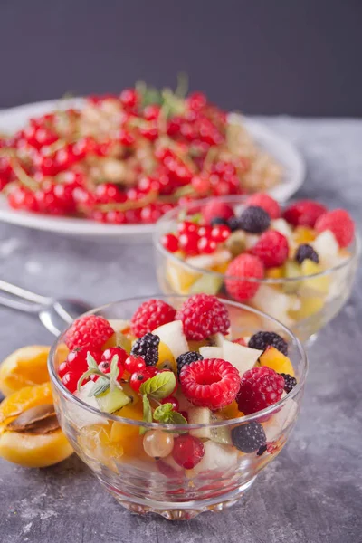 Sałatka ze świeżych owoców i jagód na miski na tle concreate — Zdjęcie stockowe