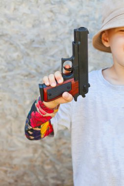 Küçük oğlan içinde bir gri t-shirt tutan oyuncak silah
