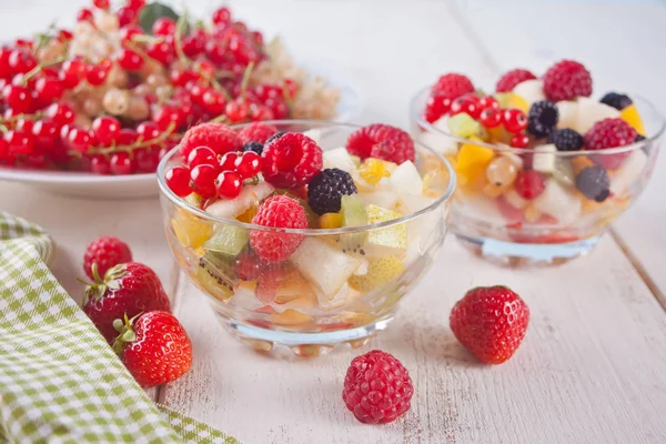 Салат зі свіжими фруктами та ягодами на мисках на білому тлі — стокове фото