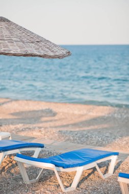 Deniz sahilinde şezlonglar ve şemsiyeler. Tatil, yaz tatilleri ve seyahat için güzel bir konsept
