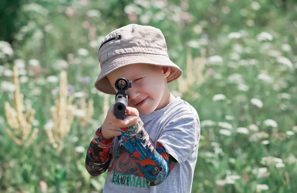 Liten pojke med leksakspistol på jakt utanför. — Stockfoto