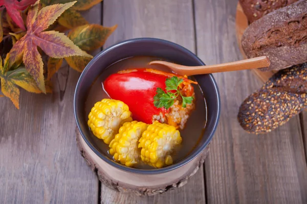 พริกไทยยัดไส้ด้วยเนื้อสับข้าวและข้าวโพดในชามบนโต๊ะไม้ อาหารร้อนฤดูใบไม้ร่วง — ภาพถ่ายสต็อก