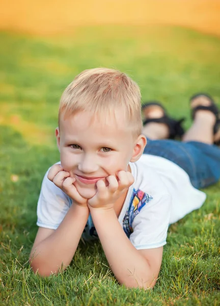 Portret uśmiechniętego chłopca leżącego na zielonej trawie. — Zdjęcie stockowe