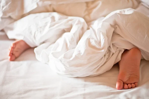 Menino menino dormindo mostrar pés sob fora de cobertor branco — Fotografia de Stock