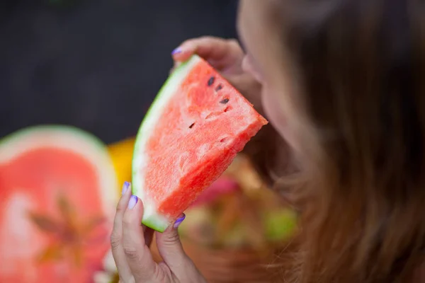 Kvinna med en bit mogen vattenmelon i en hand i en picknick. Höstskörden. Höstens koncept — Stockfoto