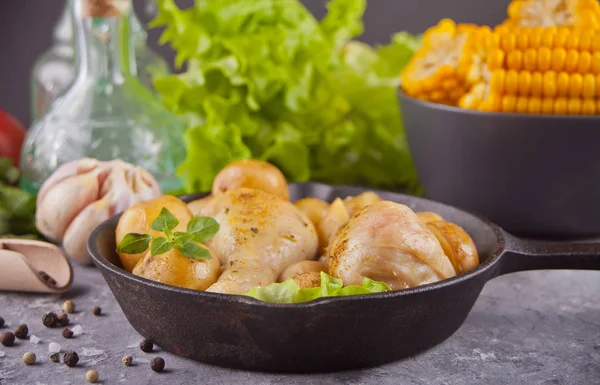 Patas de pollo asadas con patata, especias y hierbas en el sartén negro.Con verduras en el fondo. Vista superior —  Fotos de Stock