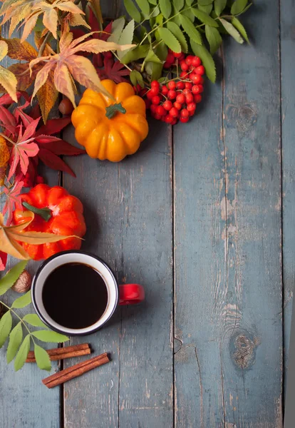 Cup of coffee with autumn leaves and small pumpkins on the old blue wooden table. Autumn harvest. Autumn concept. Top view. Copy space.