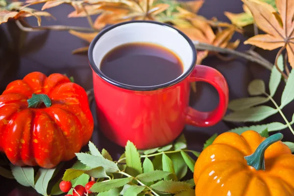 Cup of coffee with autumn leaves and small pumpkins on the old blue wooden table. Autumn harvest. Autumn concept.