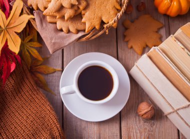 Bir fincan kahve, sonbahar yaprakları, balkabağı, kurabiyeler, tahta masadaki kitaplar. Sonbahar hasadı. Sonbahar konsepti. Üstte görüntü.