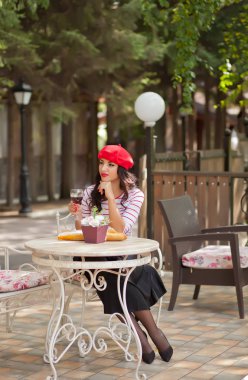 Açık hava kafede kırmızı şarap içen kırmızı şapkalı kadın
