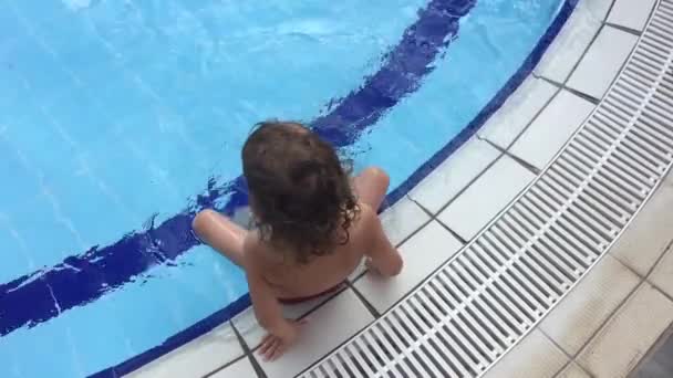スイミングプールの水を叩く小さな女の子の足 子供はプールの端に座って 彼らの足をスプラッシュ — ストック動画